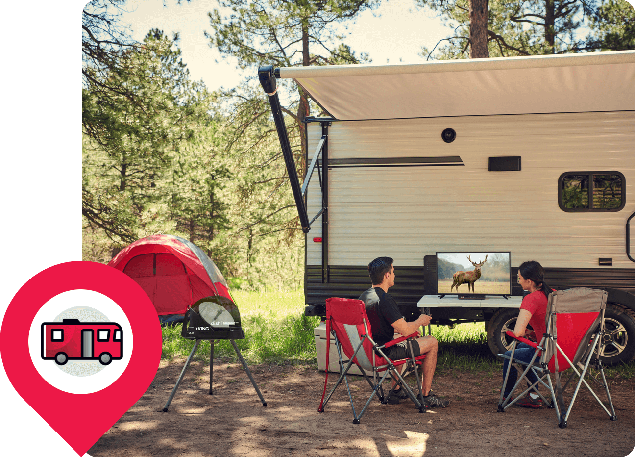 Couple sitting on camping chairs next to an RV with a television showing a deer.